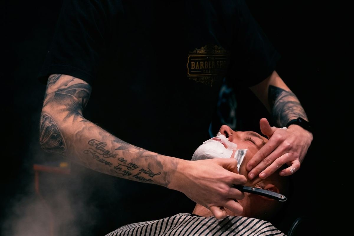 Barbeiro com toalha quente fazendo a barba de um cliente