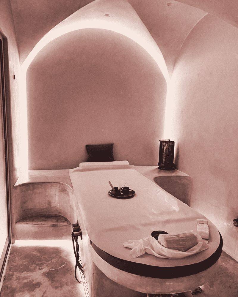 Sala de tratamento da clínica, com maca e arquitetura em arco